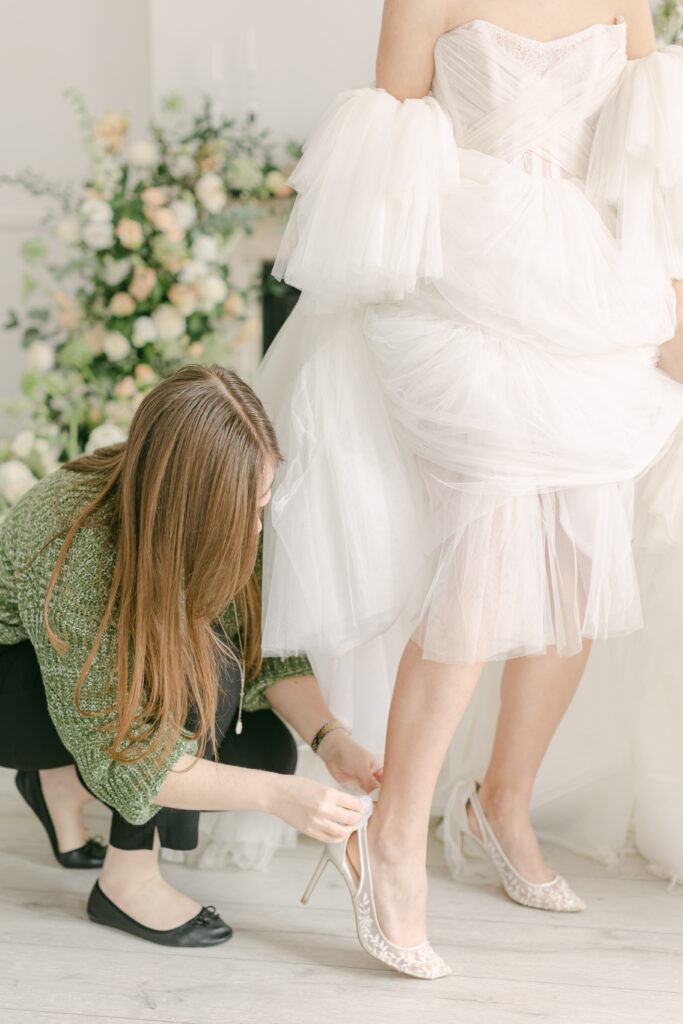 Destination wedding planner adjusting bride's shoe